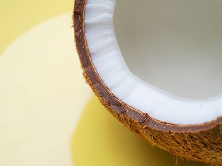 Coconut half on yellow background, copy space, texture, close upの写真素材