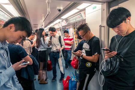 Asian People Staring at Smartphone inside Train in Shenzhen, China - April 2018