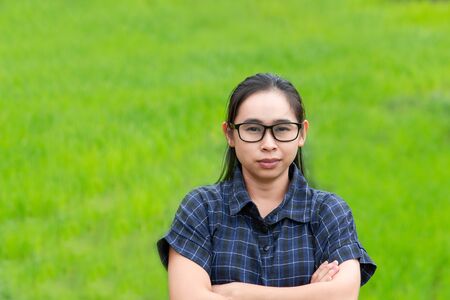 Asian farmer woman smile and cross one's arms with a look of proud on rice field background.の写真素材