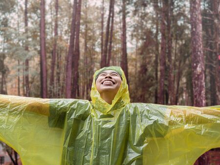 Portrait of Happy Asian woman wearing yellow raincoat stand in rain.の写真素材