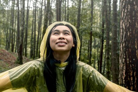 Portrait of Happy Asian woman wearing yellow raincoat stand in rain.の写真素材