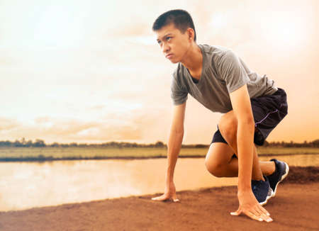 Fit and confident Asian young man in starting position ready for running. Healthy lifestyle.の写真素材
