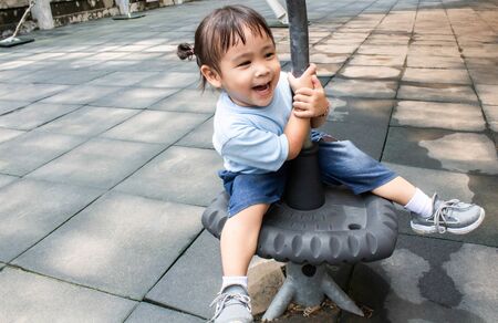 Happy asian little child girl having fun to play in the playground in summer time.の写真素材