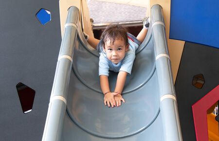 Asian little child girl having fun on slide at playground.の写真素材