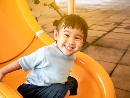 Happy Asian little child girl having fun on slide at playground.の写真素材