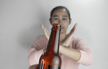 Asian woman refuses alcohol; isolated on grey background. Stop alcoholismの写真素材