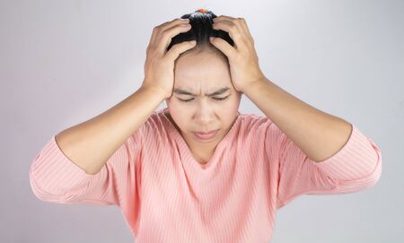 Asian young woman holding her hand to the head while have chronic severe headache migraine. Health and medical concept.の写真素材