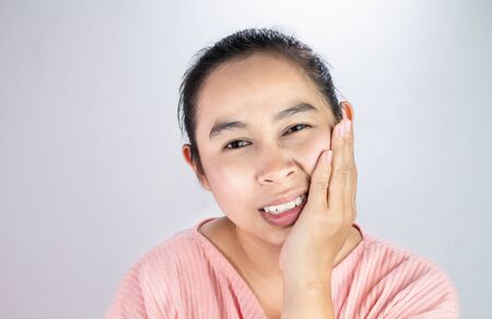 Asian woman touching cheek with hand because she is suffering of toothache. Dental care and health concept.の写真素材