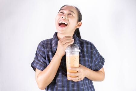 Happy Asian young woman is drinking Thai tea with milk. Popular beverage in Asia.の写真素材
