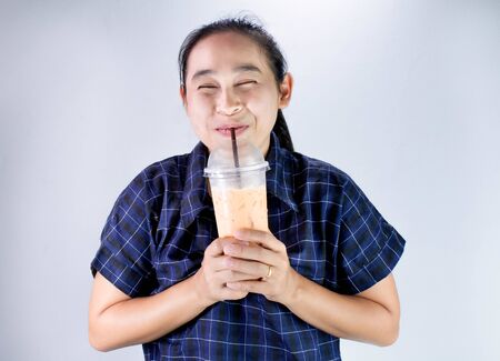 Happy Asian young woman is drinking Thai tea with milk. Popular beverage in Asia.の写真素材