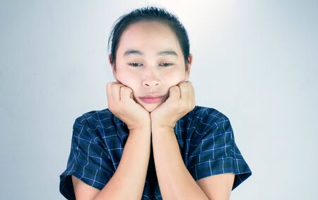 Portrait of young woman looking bored and put hands on chin isolated on a grey background.の写真素材