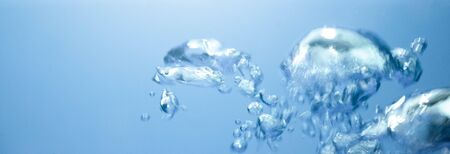 Air bubbles rising up to surface in blue pure water. Abstract background.