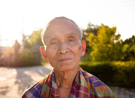 Senior Asian man with a loincloth covering his shoulders, standing over the bright sky background.の写真素材