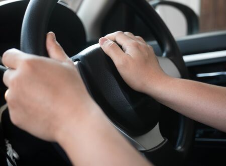 Close up inside vehicle of female hand pushing on steering wheel and honking with angry. Technology...