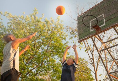 Asian elderly men playing basketball on playground on summer day. Healthy lifestyle and Healthcare...