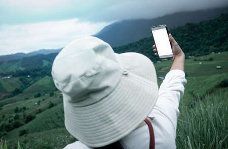 Tourist enjoy nature and take pictures with smartphone on the mountain background.の写真素材