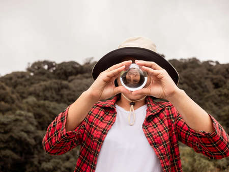Asian woman  holding and look into a magic crystal glass ball on nature background.の写真素材