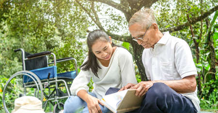 Happy disabled grandfather relaxing with granddaughter outdoor at the park. Family happy lifestyle.の写真素材