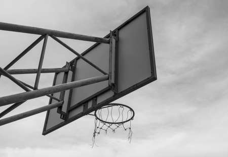The back image of the basketball board hoop with the loop on the sky background. Black and white...