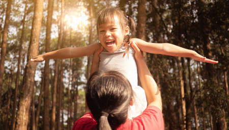 Happy mother holding little girl smiling and playing in summer on the nature.の写真素材