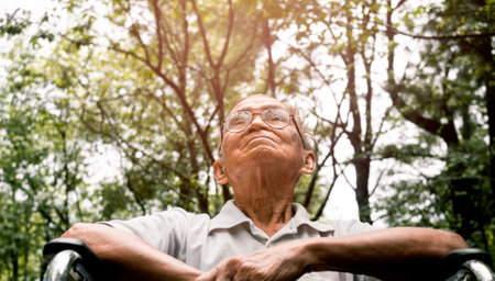 Happy senior man in a wheelchair enjoying nature in the park.の写真素材