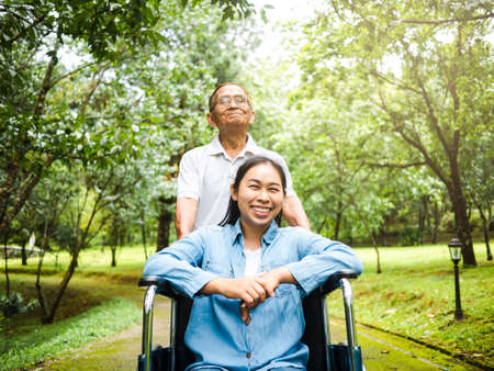 Happy senior man in a wheelchair enjoying nature in the park.の写真素材