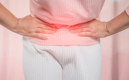 Young sick woman with hands holding her belly suffering menstrual period pain at home. Gynecology and female health concept.の写真素材