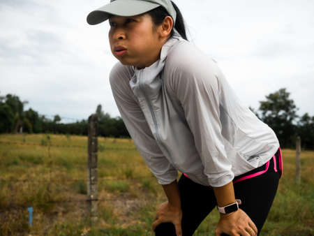 Tired female runners taking a rest after running hard on the road trail in morning training for fitness. Healthy lifestyle concept. Athlete running exercising outdoors.の写真素材