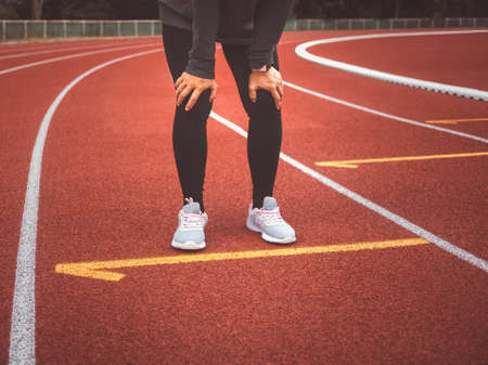 Tired female runner taking a rest after running hard on stadium track. Workout Healthy lifestyle...