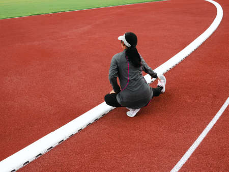 Healthy woman warming up, stretching her leg muscles in the public stadium before jogging. Workout Healthy lifestyle concept.の写真素材