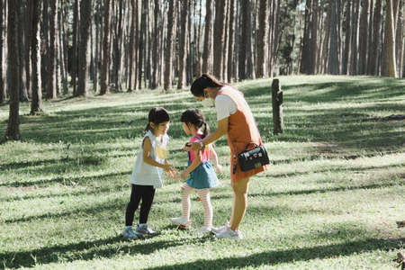 Mother and two daughters do some activities together at a camp in the woods. Family camping, spending time together on vacation.の写真素材