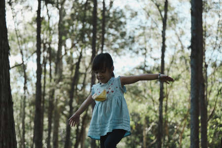 Cute little girl walking on a log in the park. child on the balance beam. Play is learning in...