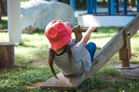 Active little girl playing on a seesaw in the outdoor playground. Happy child girl smiling and...