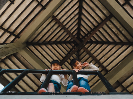 Two girls looked down from the tower in the playground with smiling faces. Family outdoor recreational activity.の写真素材