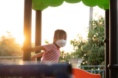 Happy little girl playing slide at playground. An active little girl in the outdoor playground. Healthy summer activity for children.の写真素材