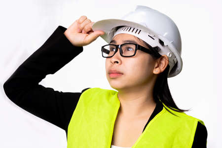 Confident female engineer wearing a helmet and looking into the distance isolated on white background in studio.の写真素材
