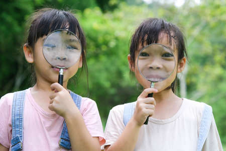 Children learn and explore nature with an outdoor magnifying glass. Curious child looks through a...