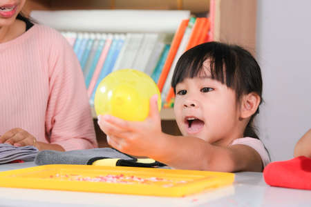 Little girl is learning and doing electrostatic science experiments with balloons in the classroom....