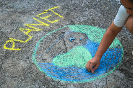 Young woman drawing with colorful chalk on asphalt.  Asian woman paints a beautiful world with the...