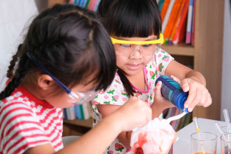Children are learning and doing science experiments in the classroom. Two little sisters playing science experiment for home schooling. Easy and fun science experiments for kids at home.の写真素材