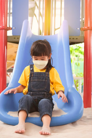 Cute little girl having fun in the outdoor playground. Young girl playing slides in the park. Healthy summer activity for children.の写真素材