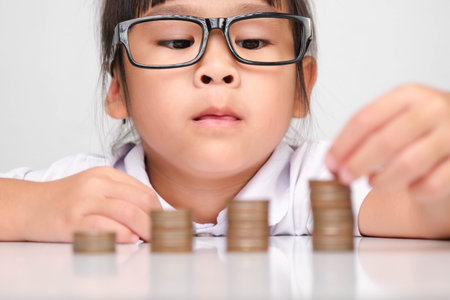Cute asian little girl making stacks of coins. Little kids save money for future education.の写真素材