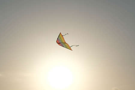 Colorful kite with flying tail in the sunset sky.