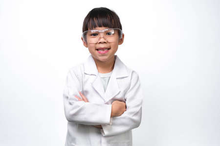 Portrait of a smiling little girl with glasses standing with her arms crossed in a doctor or science suit on a white background. Little scientist.の写真素材