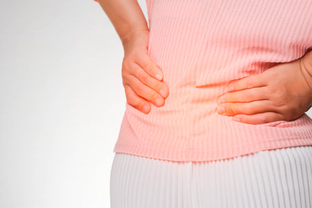 Back view of woman suffering from backache, waist pain, muscle or chronic nerve pain in her back after working. close up. Health problems, concepts of diseases of the musculoskeletal system.の写真素材