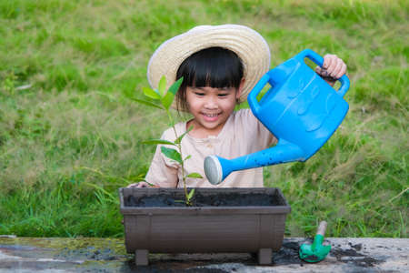 Little girl wearing a hat helps her mother in the garden, a little gardener. Cute girl planting flowers in pots for sale. family small businessの写真素材