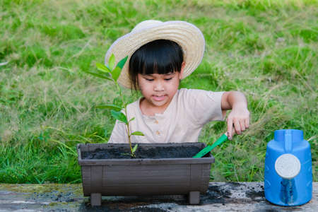 Little girl wearing a hat helps her mother in the garden, a little gardener. Cute girl planting flowers in pots for sale. family small businessの写真素材