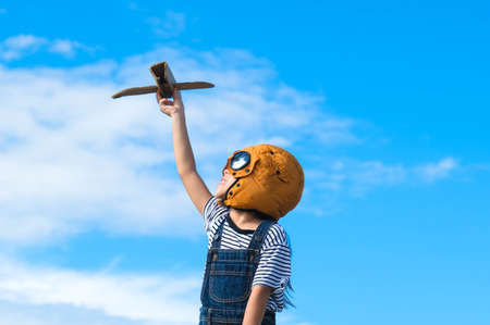 Cute little girl running through the meadow on a sunny day with a toy plane in hand. Happy kid...