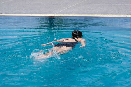 Beautiful young asian woman happy and smile in swimming pool. Asian woman in swimsuit is swimming in the blue clean water of the swimming pool for exercise. Travel and summer vacation concept.の写真素材