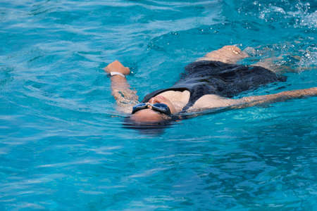 Beautiful young asian woman happy and smile in swimming pool. Asian woman in swimsuit is swimming in...